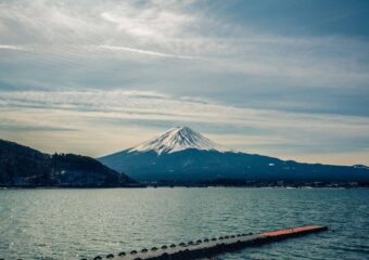 A mountain with snow on top of it and water in the foreground.